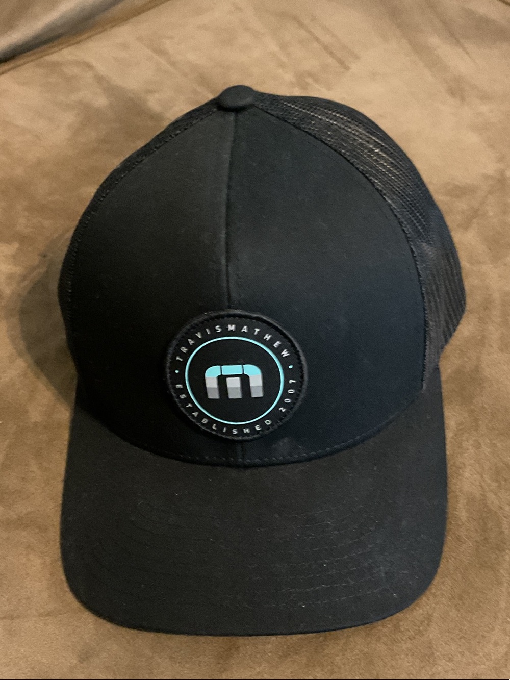 Travis Mathew Black Trucker Hat with Teal Logo Patch